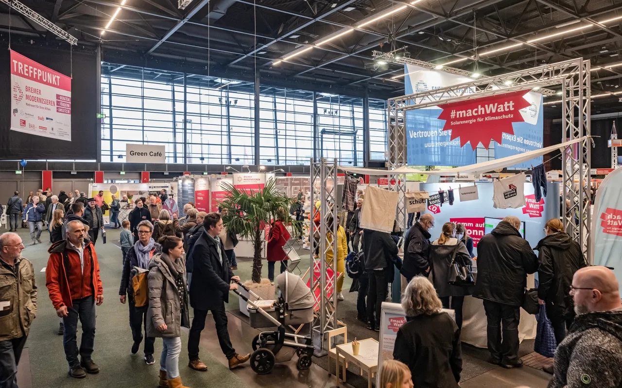 Blick von schr&auml;g oben auf den Solarstand auf den Bremer Altbautage - viele Personen stehen und Laufen in der Halle 7