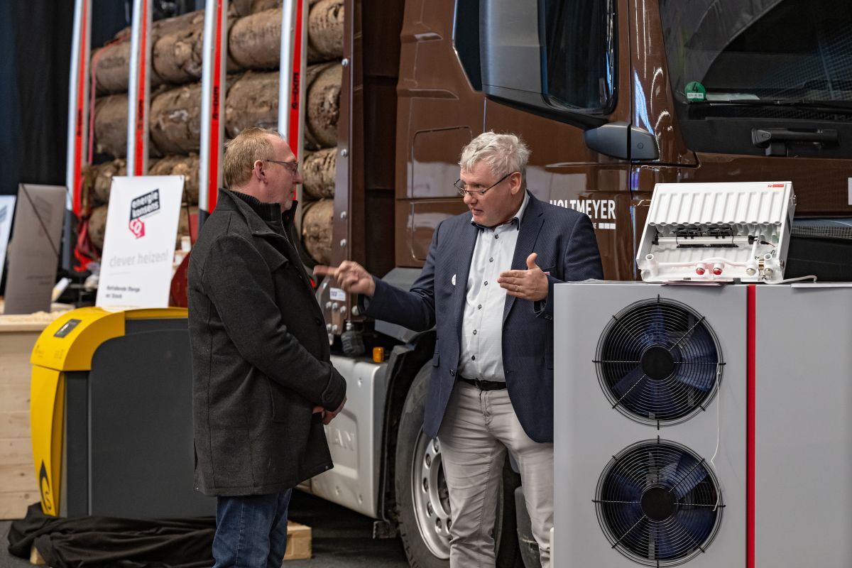 Mann wird von einem anderen Mann beraten, rechts steht eine Wärmepumpe