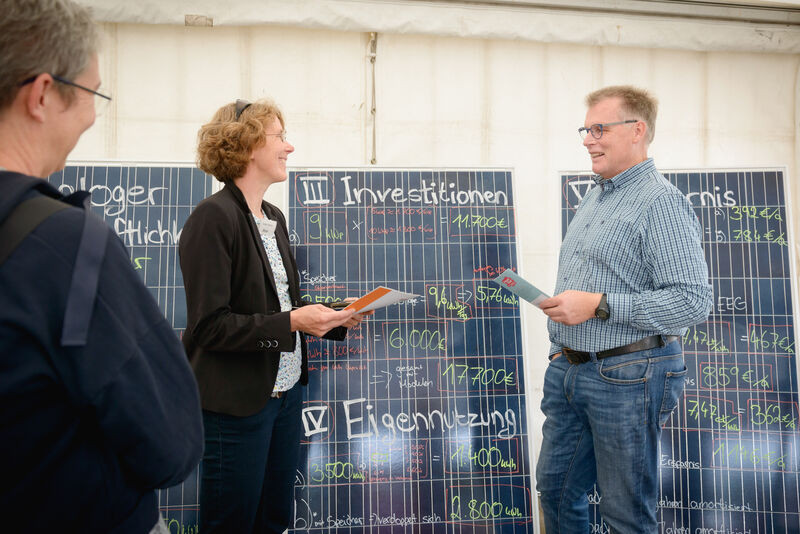 Energieberaterin Siecke Martin vom BUND Bremen berät Mann vor Solarmodulen, auf denen einen Rechnung steht.
